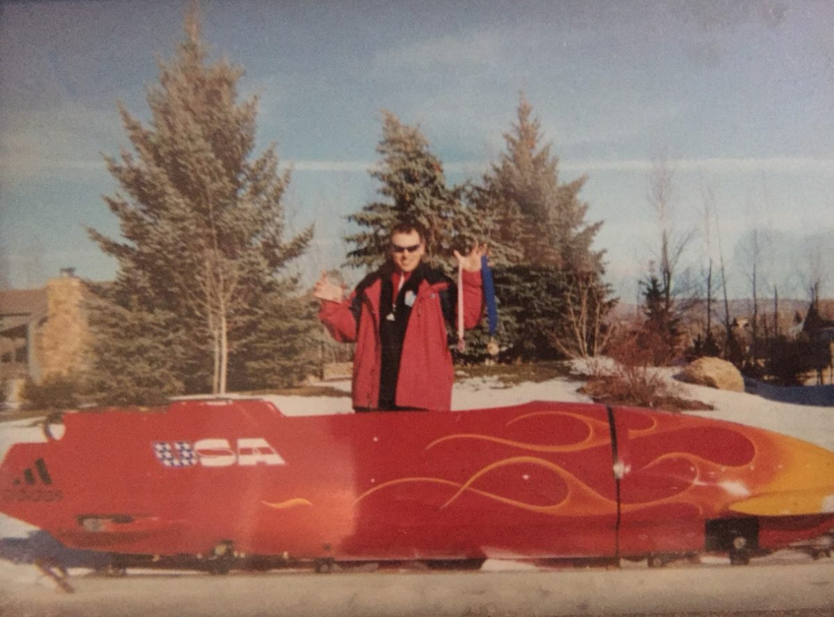 Matt standing behind the Four Man sled with his medals.