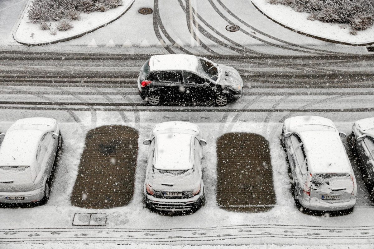 A car drives past snow-covered cars parked in a car park after snowfall in Rzeszow, Poland, November 21, 2025. Agencja Wyborcza.pl/Patryk Ogorzalek via REUTERS
